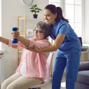 Physical therapy professional helping an older woman lift weights