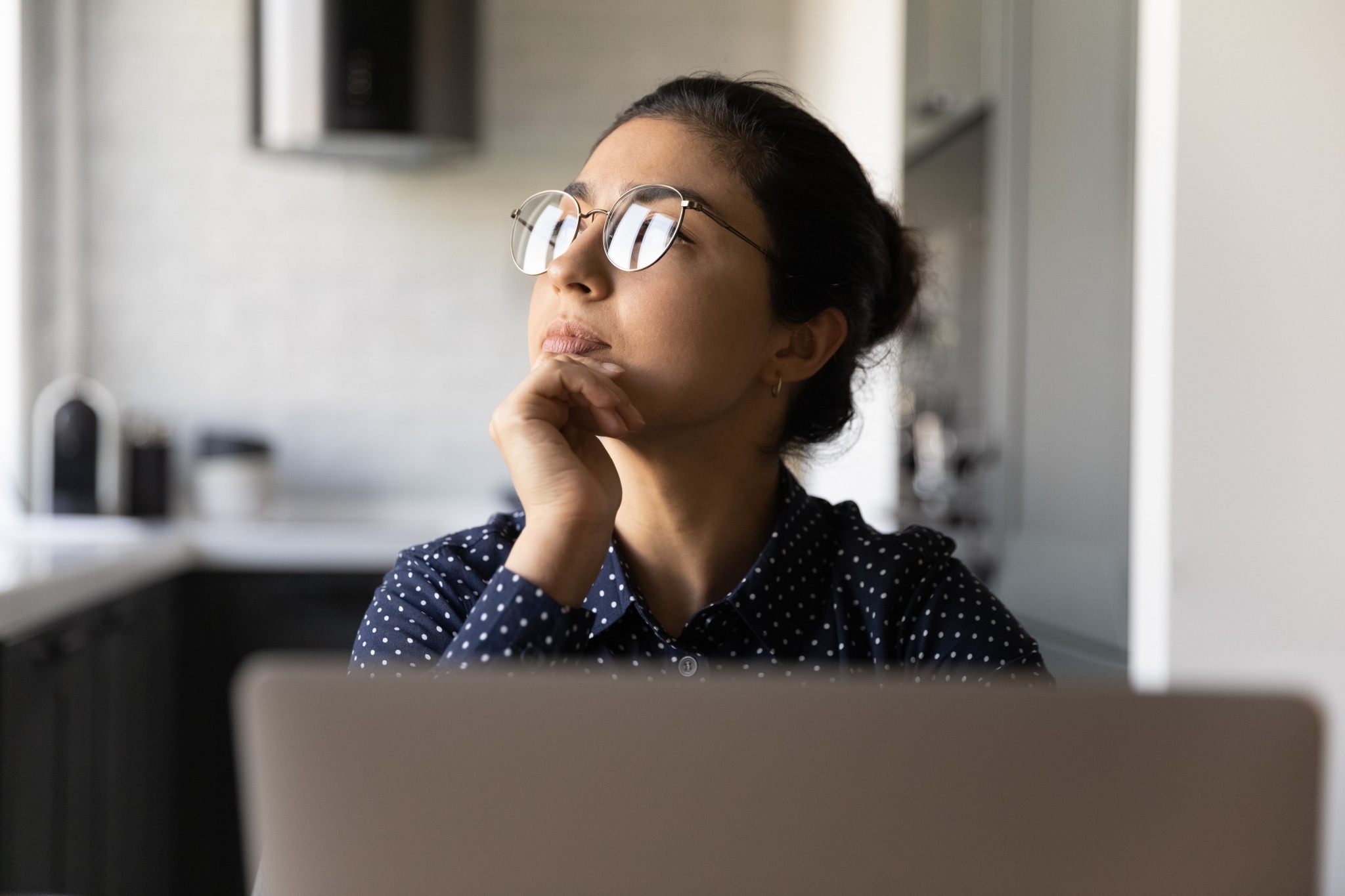 Asian woman deep in thought at her desk