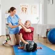 Female physical therapy professional high fiving an older patient