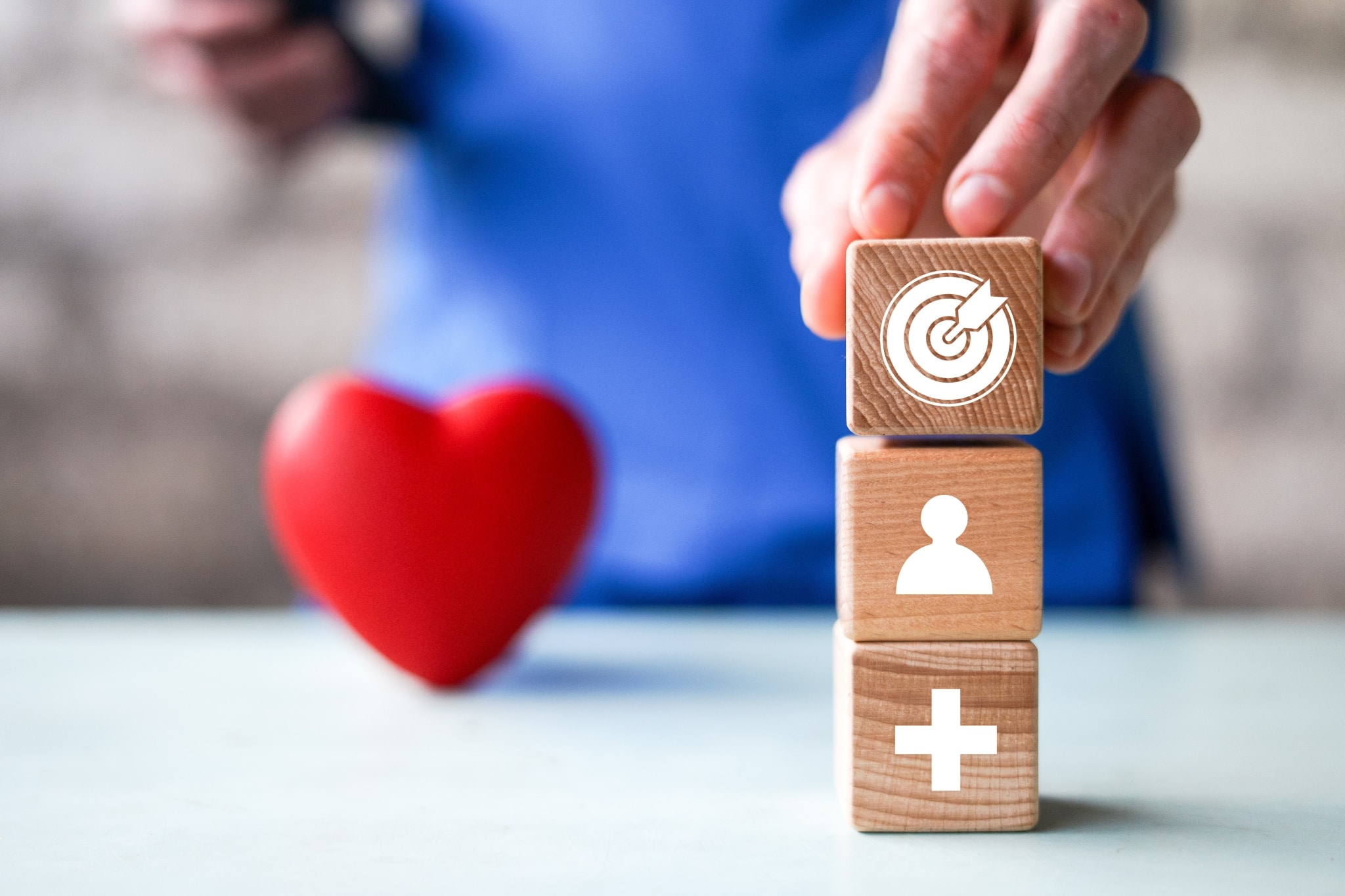 Close up of a medical professional stacking blocks with healthcare symbols