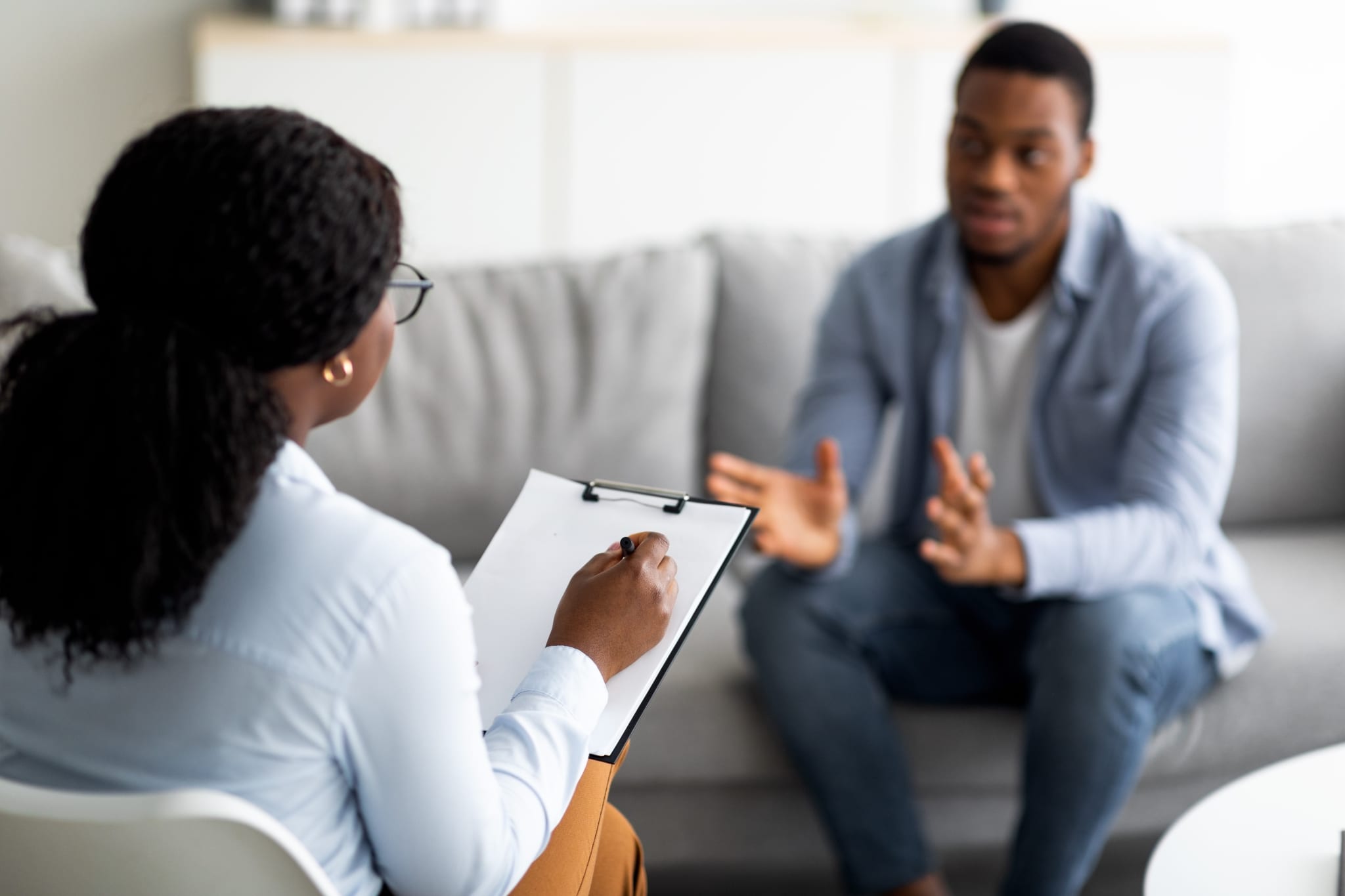 African-American counselor listening to a man speak and taking notes