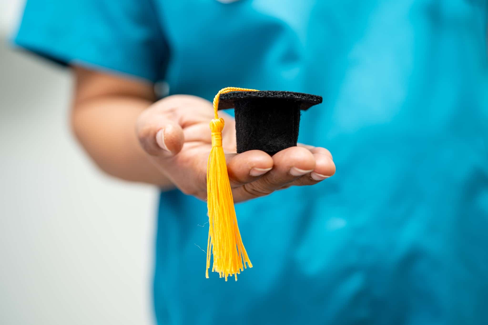 Close up of a nurse holding a miniature graduation cap