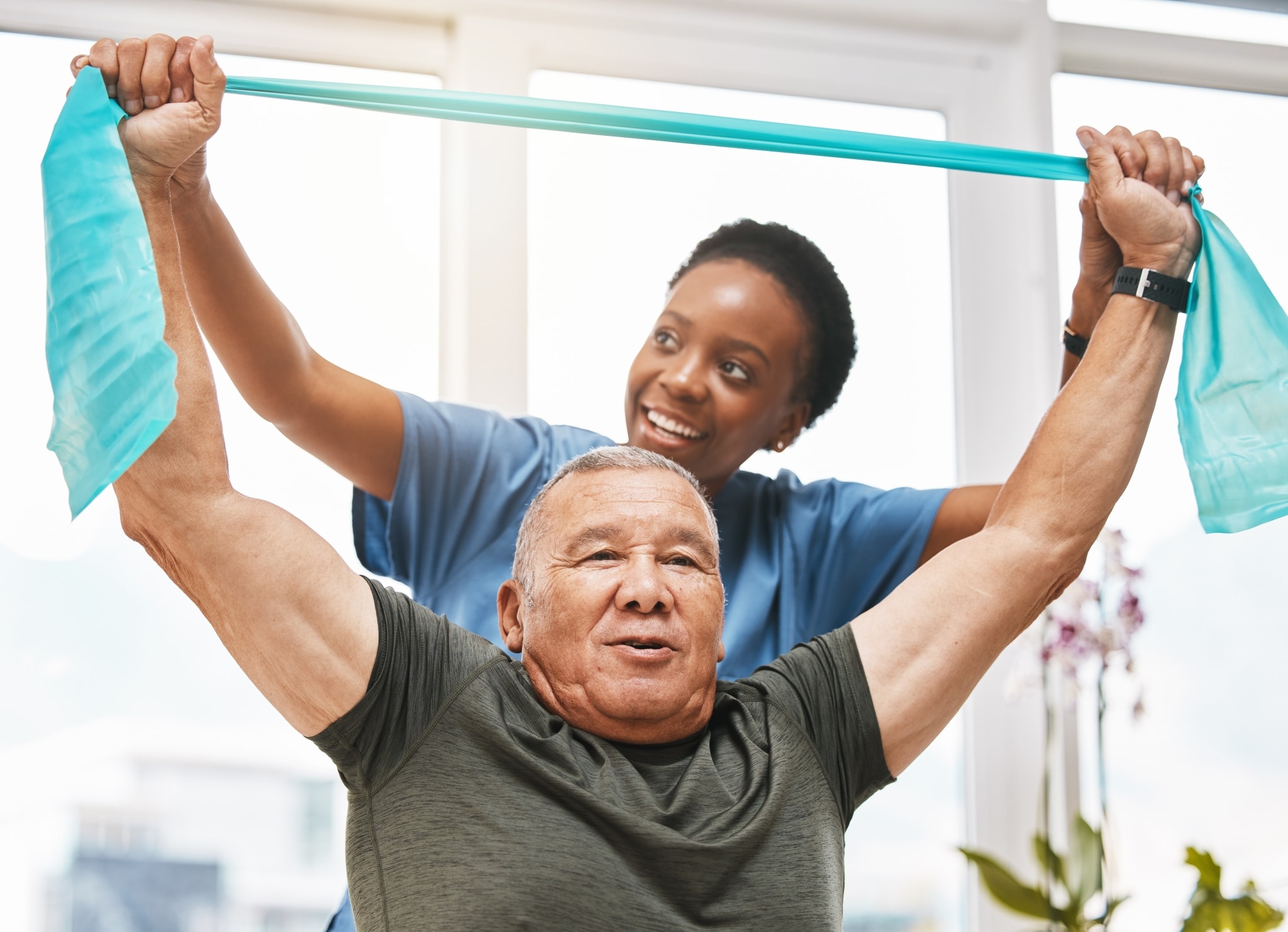 African-American woman helping an older man use an exercise band