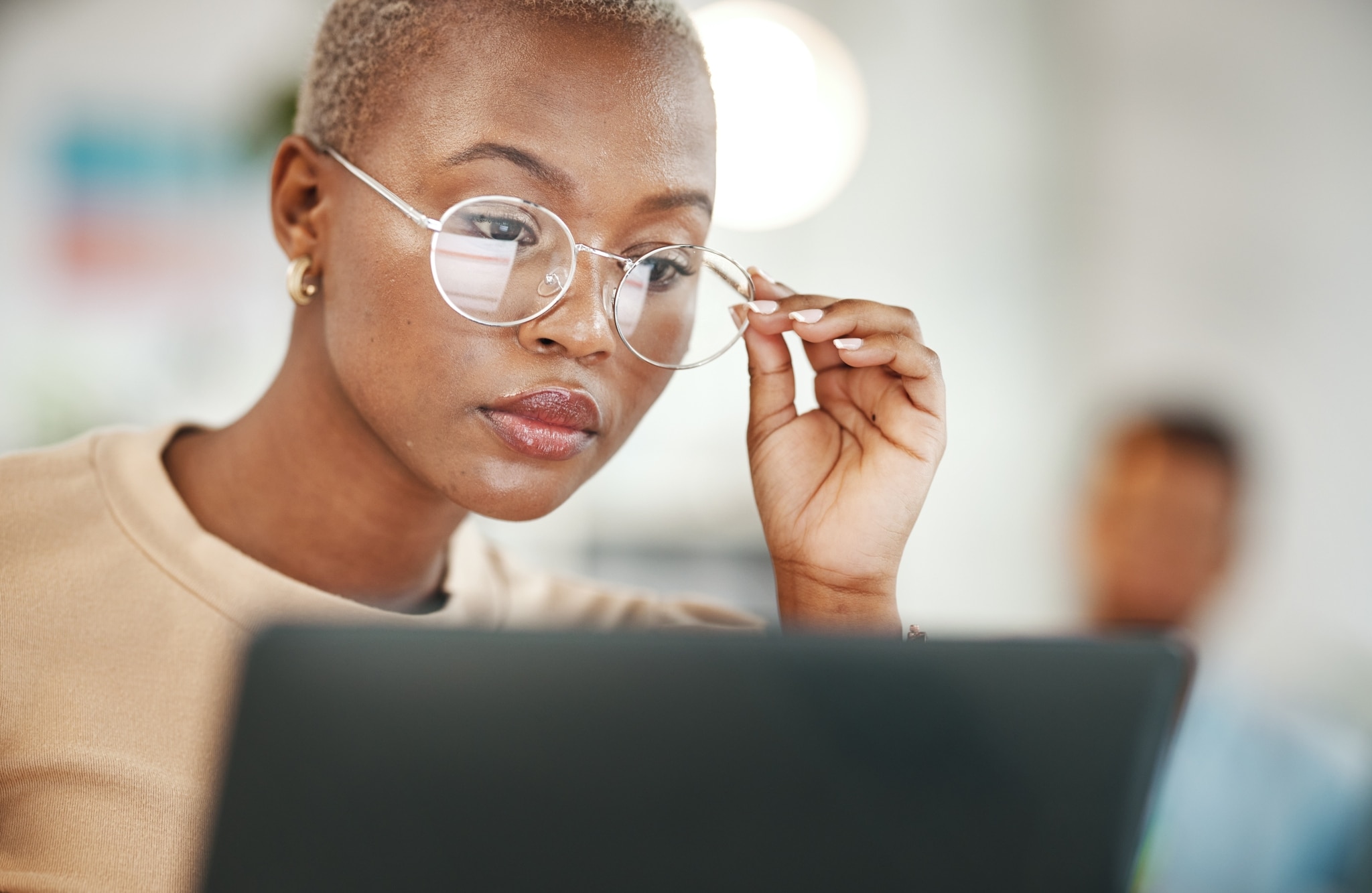African-American woman wearing glasses and using a laptop