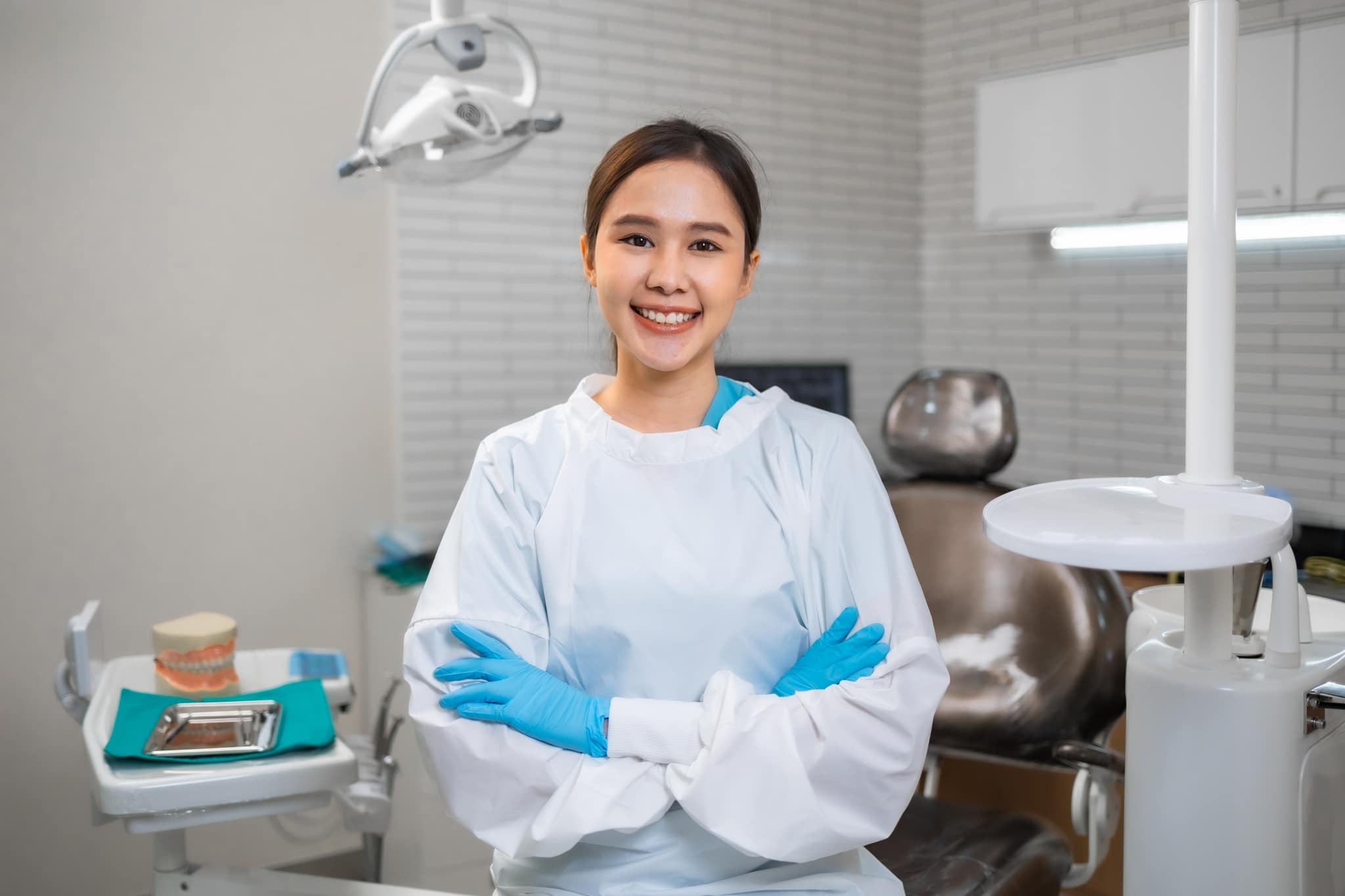 Asian Dental Assistant smiling in an exam room with protective gear