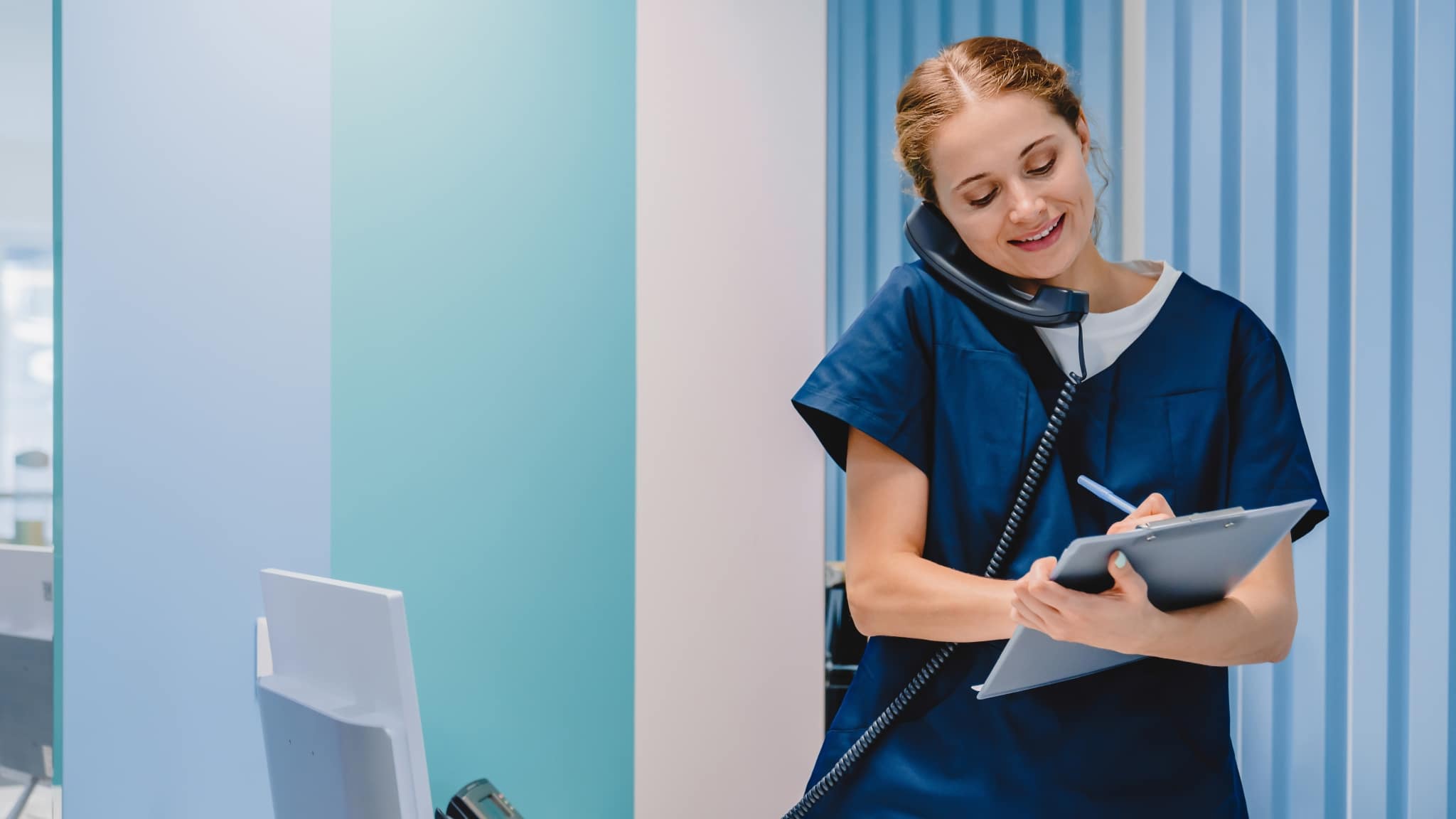Smiling Dental Assistant taking notes while on the phone