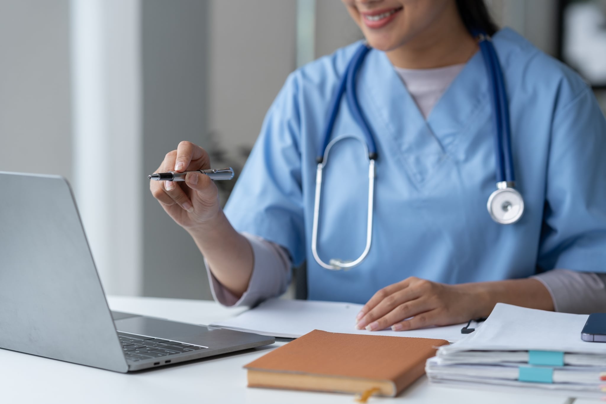Close up of a nurse using a laptop and taking notes