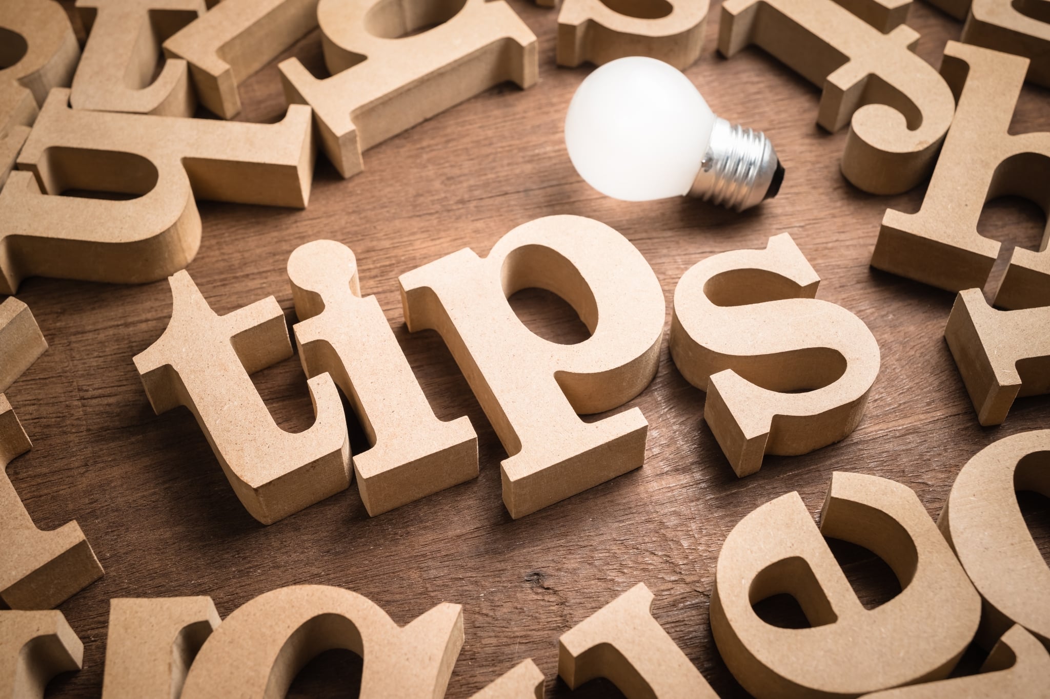 Tips is spelled in scattered wooden letters next to a glowing lightbulb