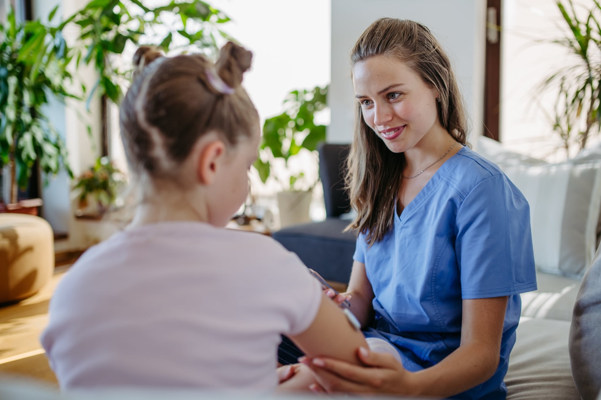 Female nurse in scrubs treating a young girl