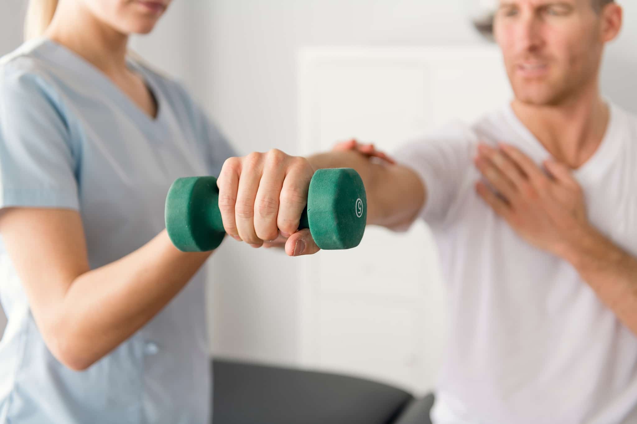 Close up of a male patient lifting weights in physiotherapy