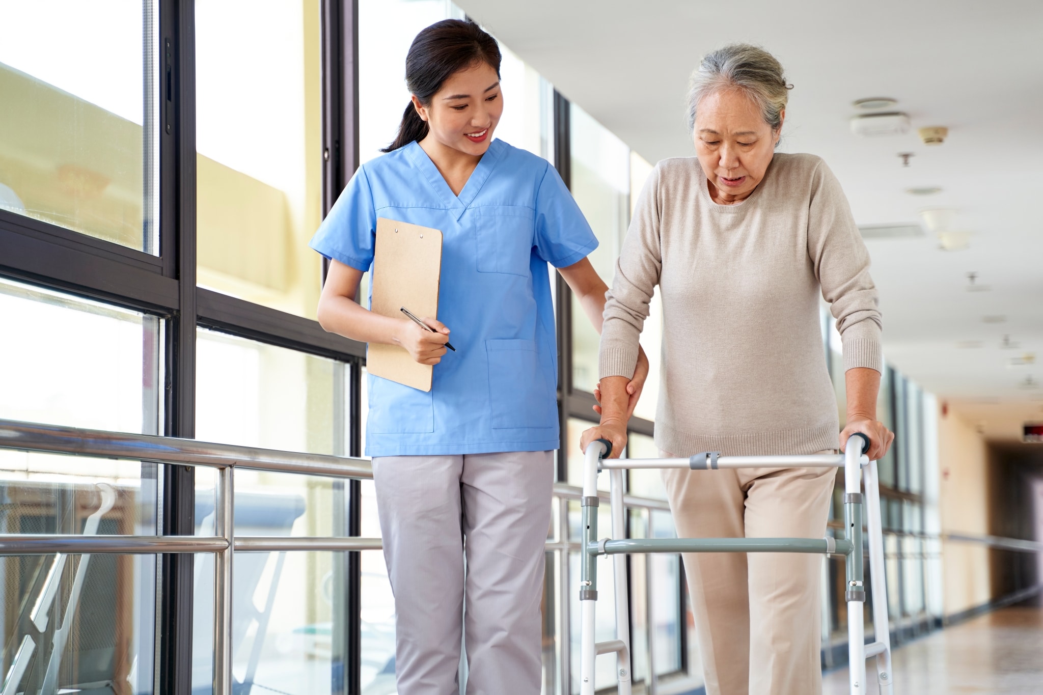 Asian medical professional helping a senior woman use a walker
