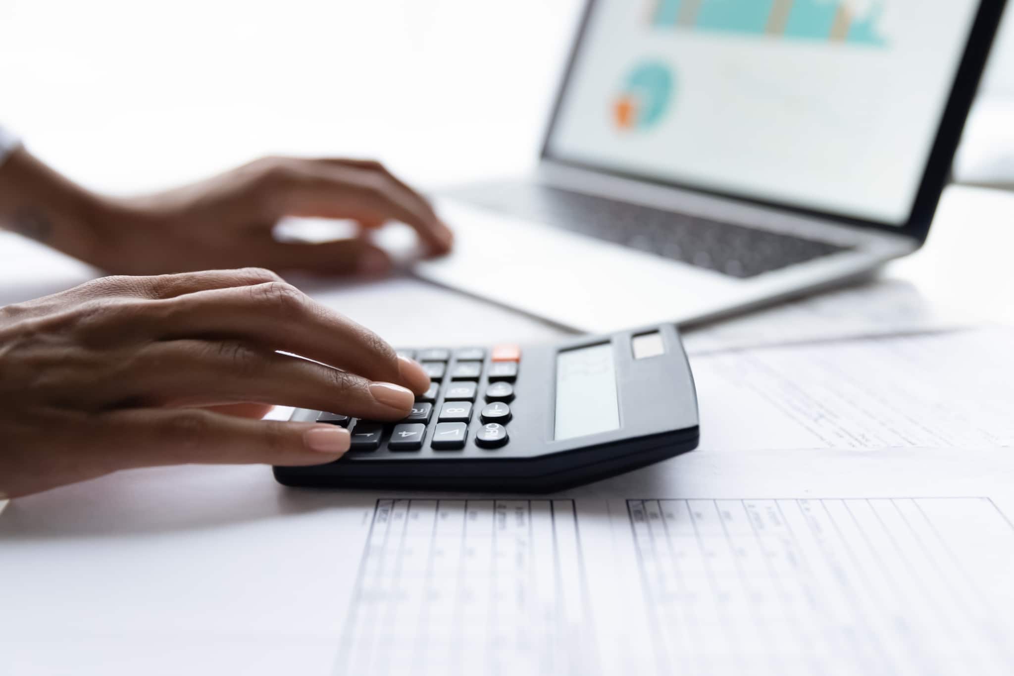 Close up of an African-American woman using a calculator and laptop