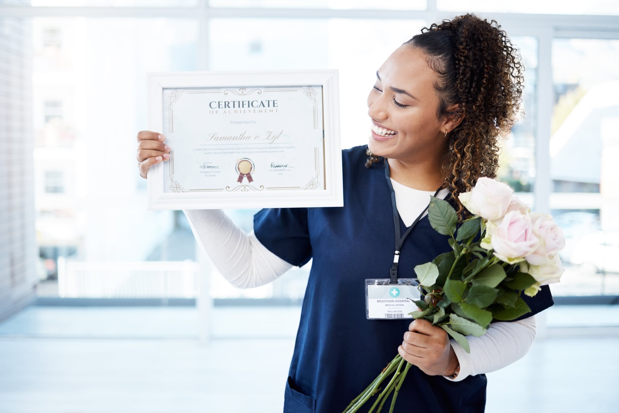 African-American medical professional holding flowers and a framed certificate