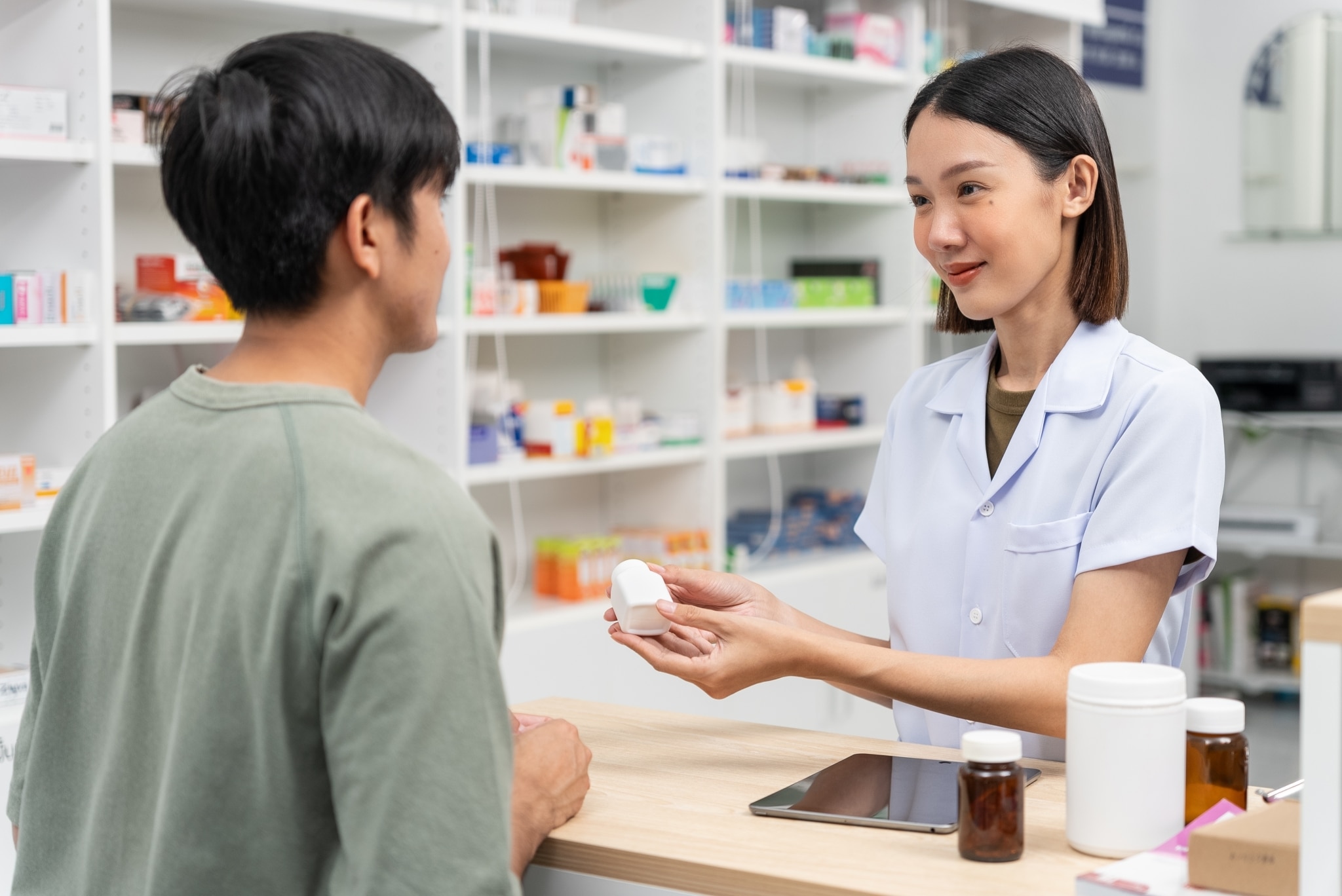Asian pharmacy technician speaking with a customer